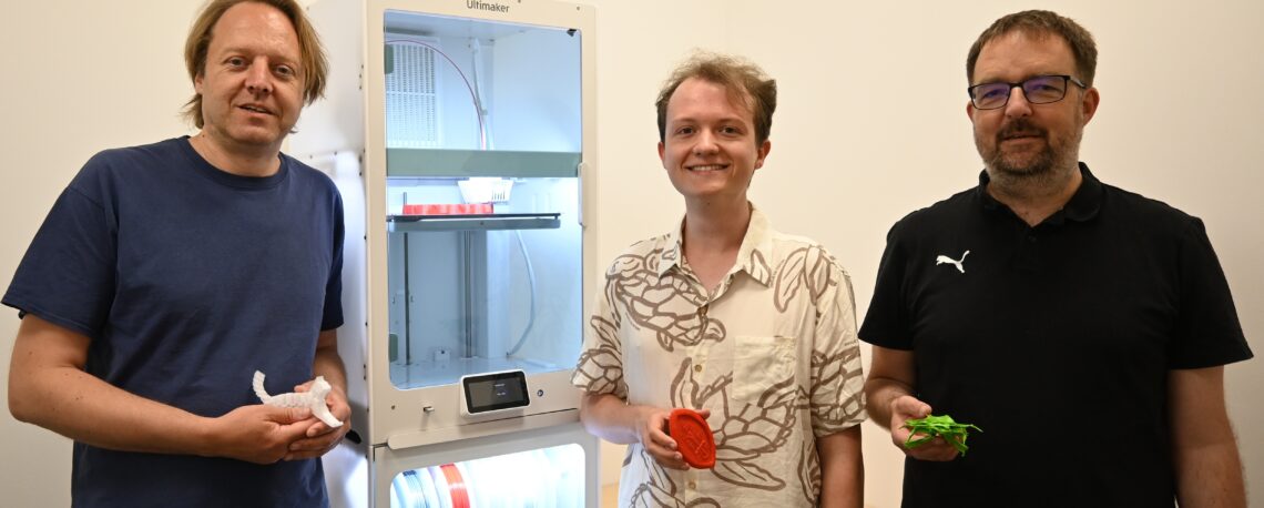Das Foto zeigt von links Dr. Carl-Christian Fey, den Geschäftsführer des DigiLLab, Kai Weeber, den Mitarbeiter im Projekt New Normal, und Prof. Dr. Ingo Kollar, Professor für Pädagogische Psychologie und wissenschaftlicher Leiter des DigiLLab, im 3D-Teaching Lab vor dem 3D-Drucker